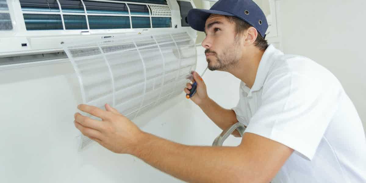 Technician cleaning a wall air conditioner filter