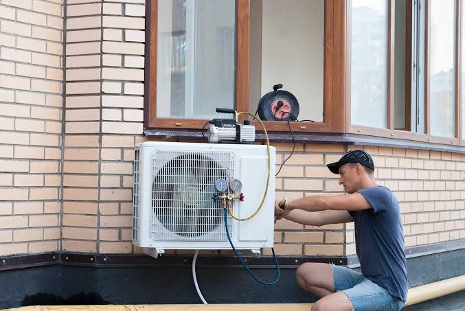 Technician connecting gauges to an outdoor air conditioning unit