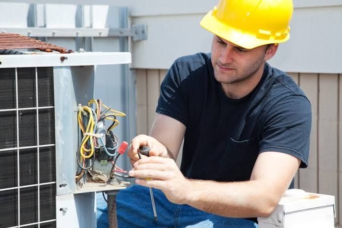 Technician repairing wiring on an outdoor air conditioner