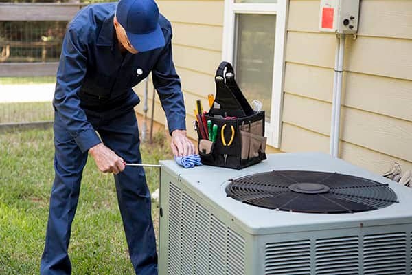 Technician inspecting a residential outdoor air conditioning unit