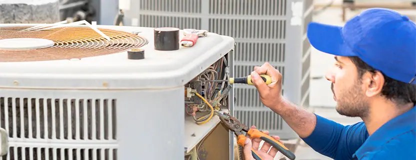 Technician performing maintenance on an outdoor air conditioning condenser