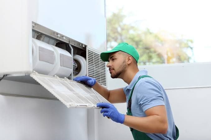 Technician removing a dirty air filter from an indoor unit