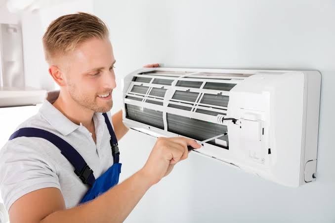 Technician checking a wall-mounted air conditioner during a service visit